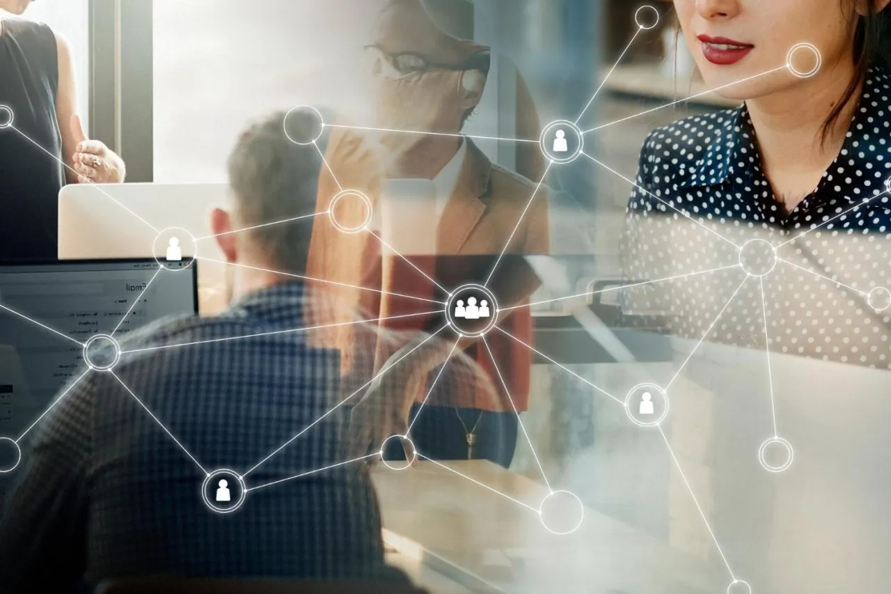 People working at computers with a digital overlay of a connected network of profile icons.